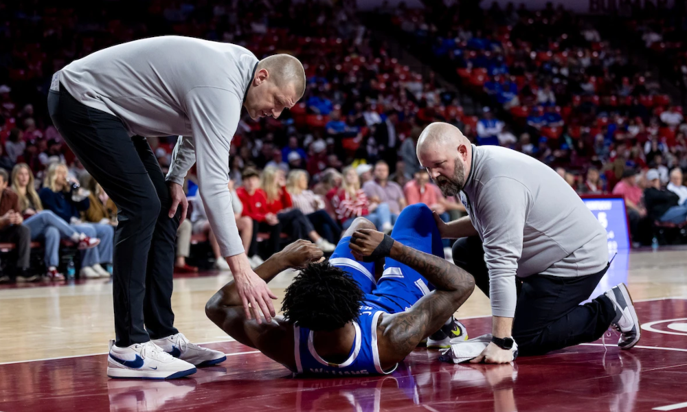 Mark Pope helps Kentucky big man Amari Williams off the floor after an ankle injury.